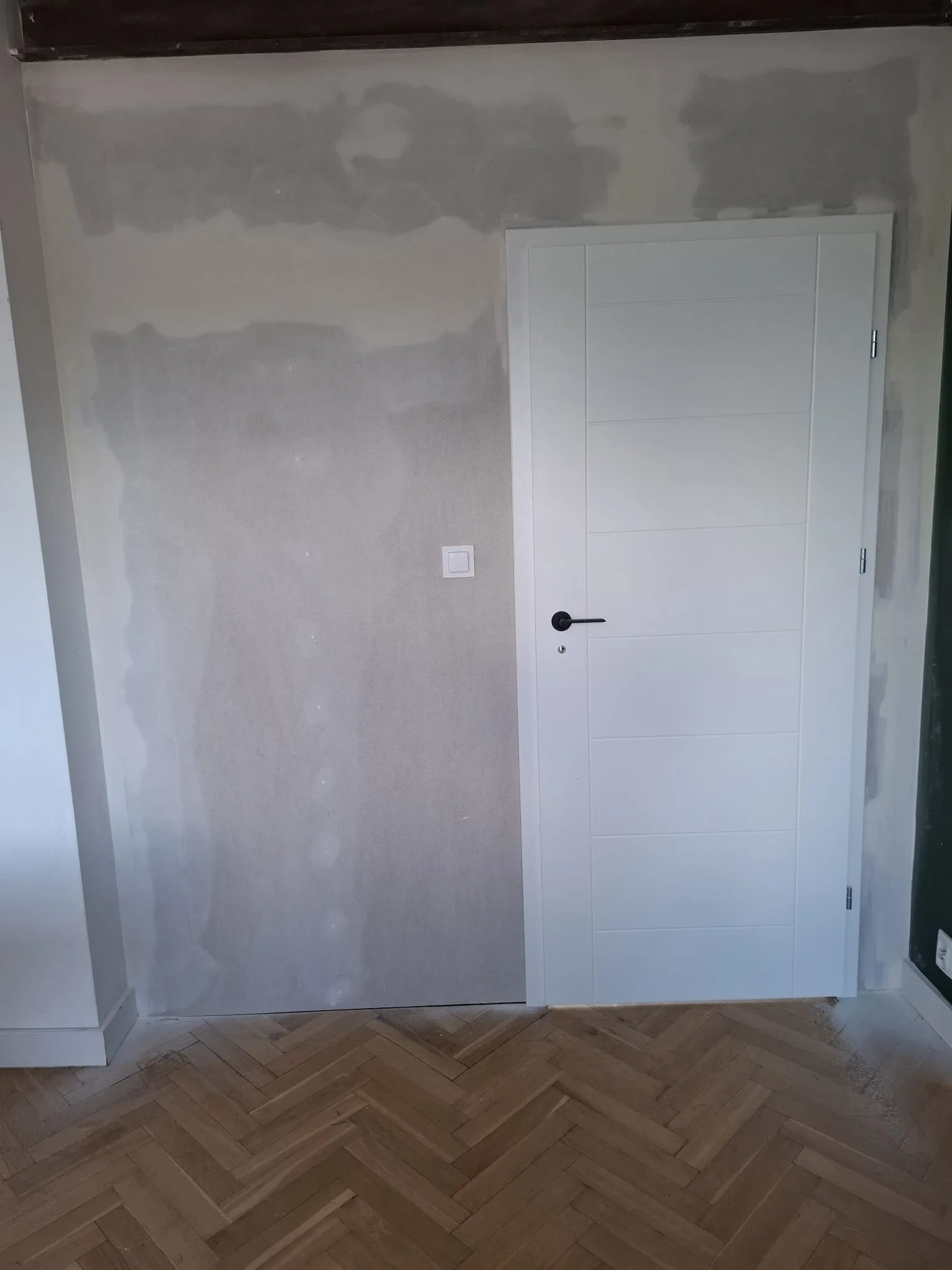 Ściana z gładzią oraz montowane drzwi wewnętrzne w nowoczesnym wnętrzu