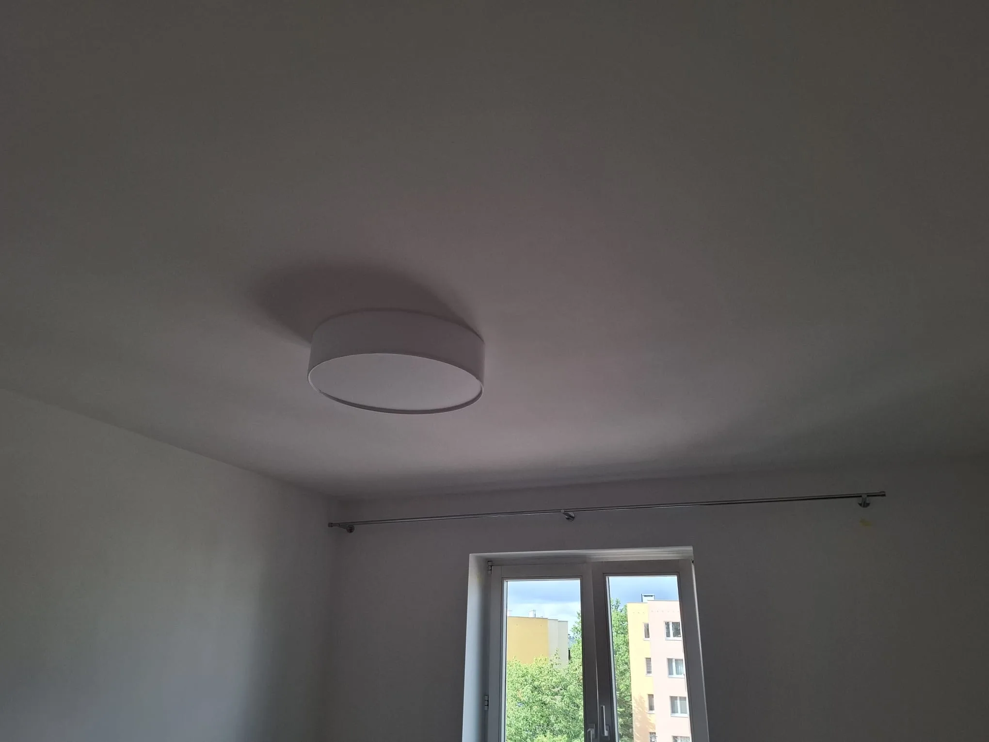 Powierzchnia sufitu po malowaniu oraz nowa lampa sufitowa w jasnym pomieszczeniu