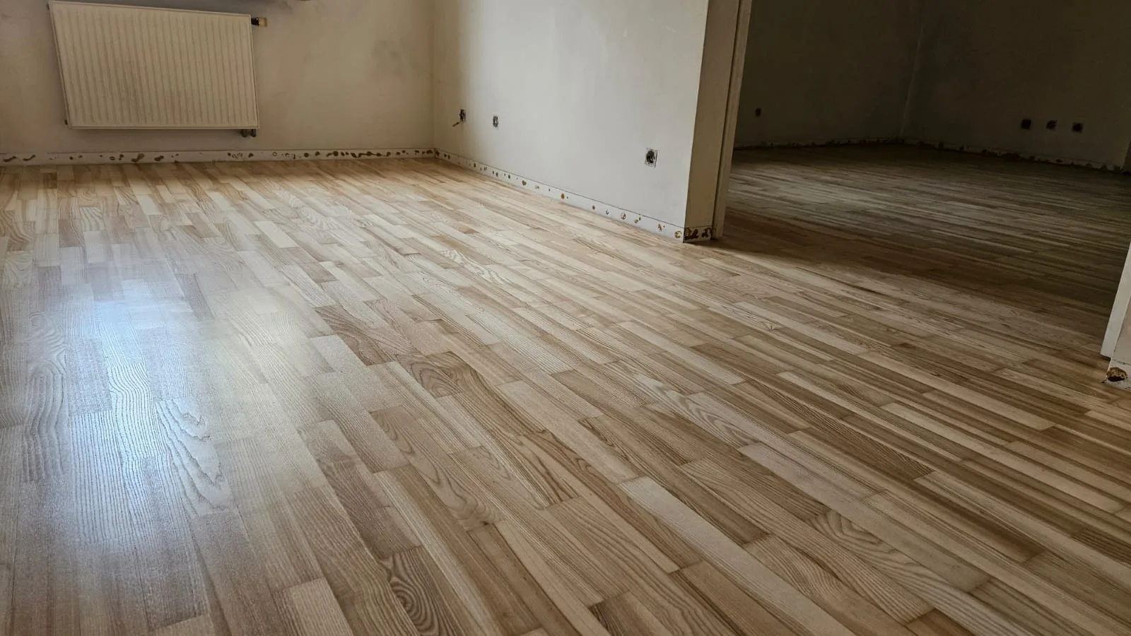 Nowoczesne wnętrze z nowo ułożoną podłogą z paneli, widoczne detale wykończenia